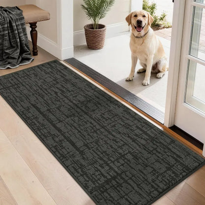 Dog standing on a doormat at the entrance of a home with a patterned rug.