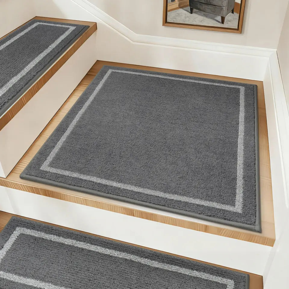 Gray stair runners with border design on wooden stairs.
