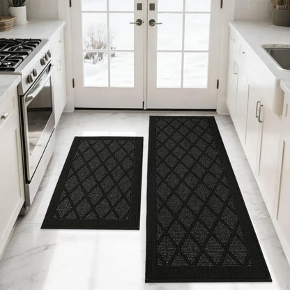 Black patterned rug on a white kitchen floor with white cabinets and appliances.
