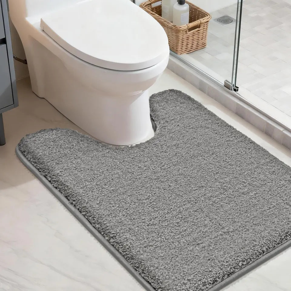 Gray u shaped toilet rug in front of a toilet in a bathroom setting